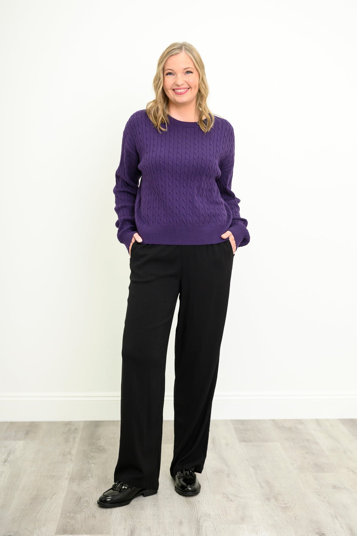 Front view of a vibrant amethyst knit top and black trousers, highlighting a comfortable, relaxed silhouette.