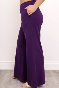 Side view of a woman wearing premium royale purple wide-leg knit pants with a clean draped silhouette.