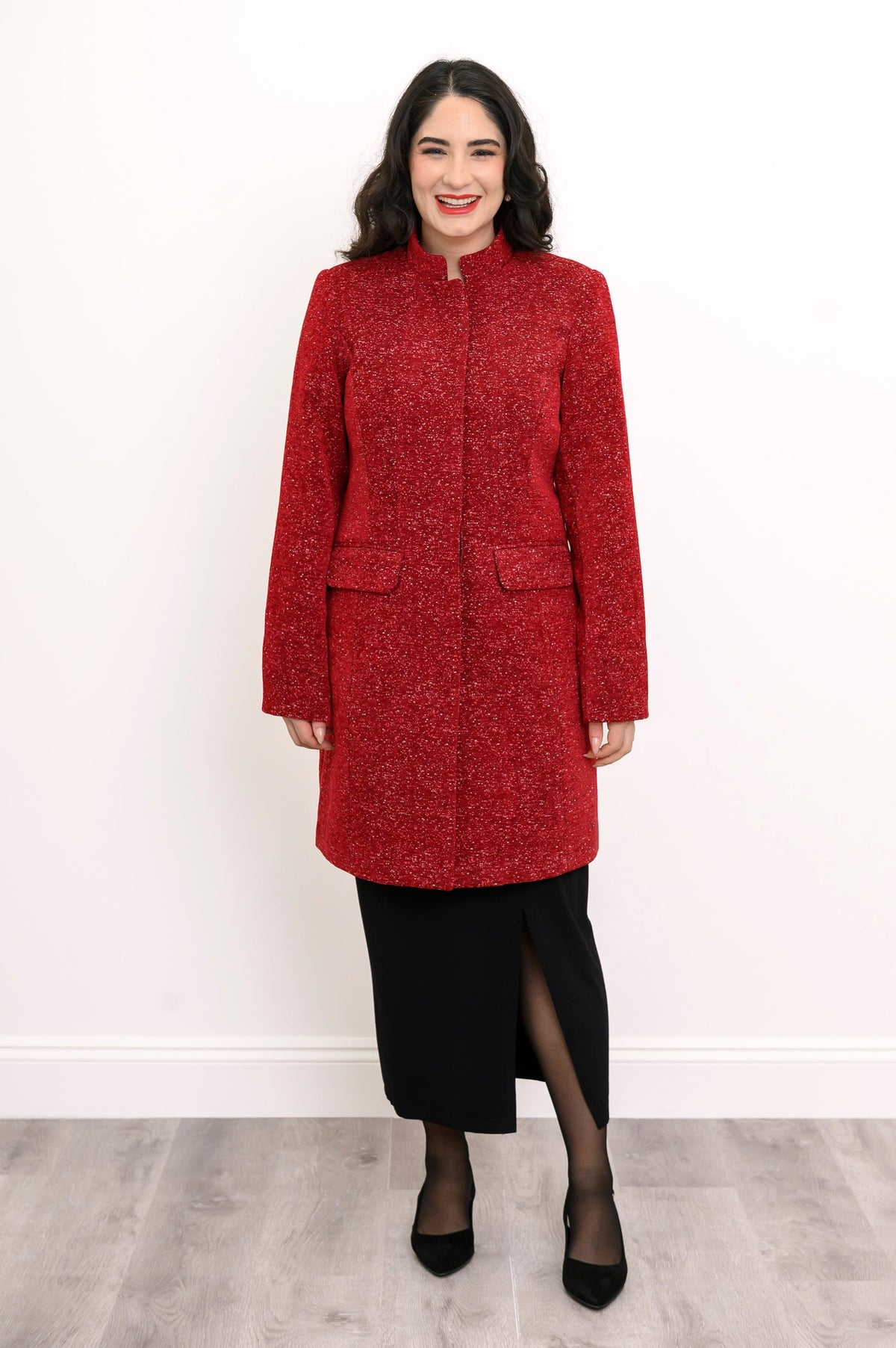 Woman smiling in long red boiled wool coat with mandarin collar styled with black pencil skirt