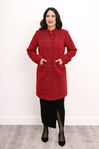 Woman wearing red collared coat with hands in pockets and a black skirt