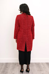 Back view of woman wearing long wool coat in red with white sparkles and split hem