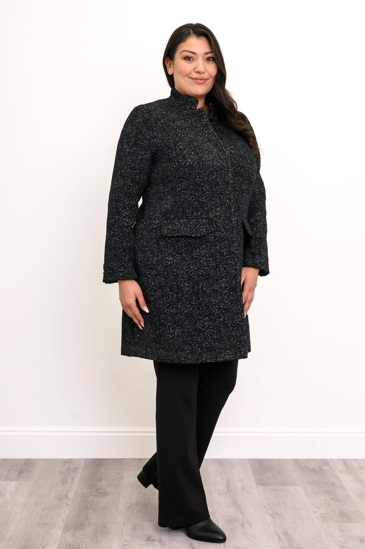 Side view of woman wearing long black coat with mandarin collar and flap pockets
