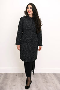 Woman smiling in long black boiled wool coat with mandarin collar styled with black pencil skirt