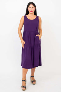 Woman standing with hands in pockets wearing plum tiered dress