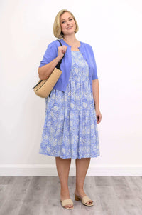 Woman in Juni Dress with lavender cardigan, holding a straw handbag