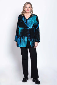 Woman facing forward in a black and blue Batik blouse with black pants and boots