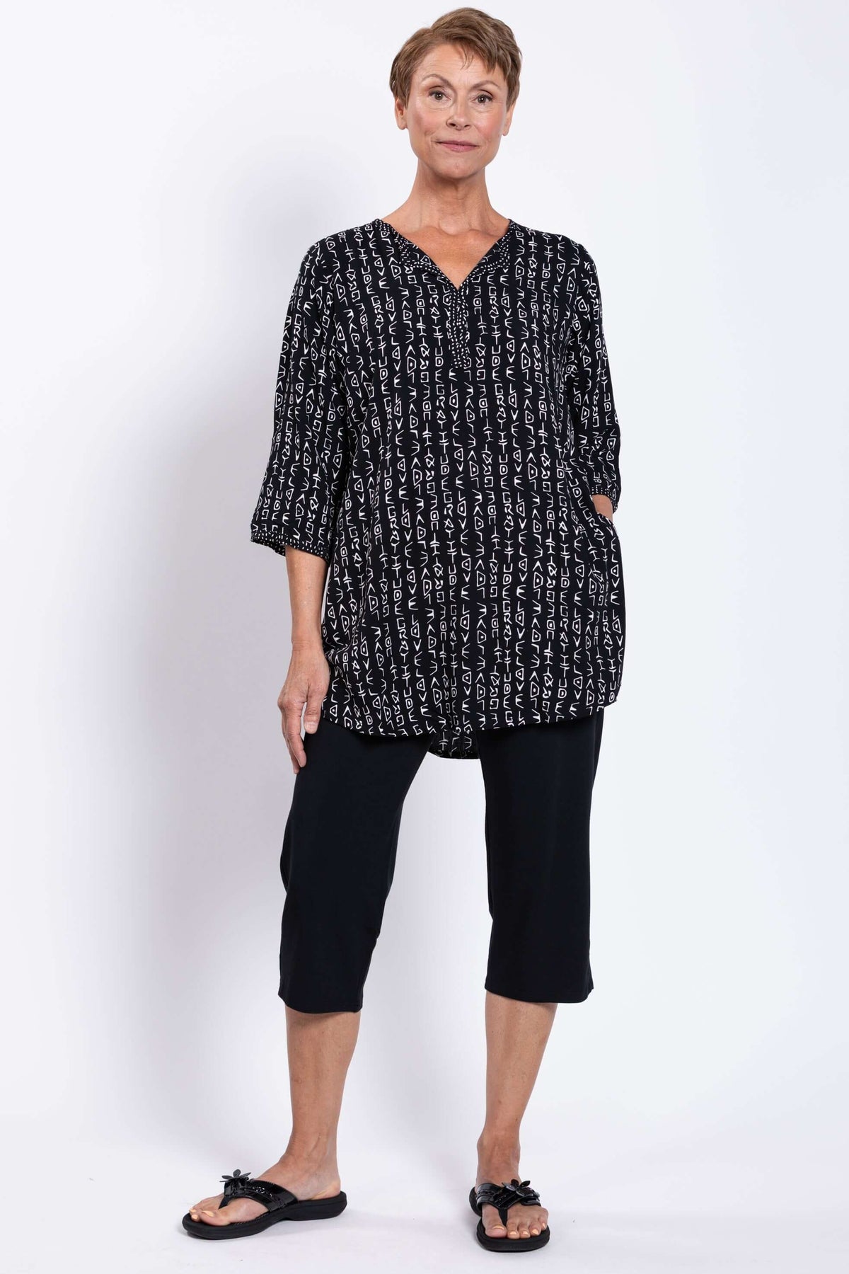 Woman in a black Batik blouse with side pockets and white geometric pattern, hands in pockets