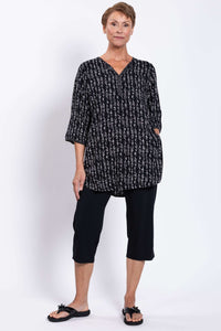 Woman in a black Batik blouse with side pockets and white geometric pattern, hands in pockets