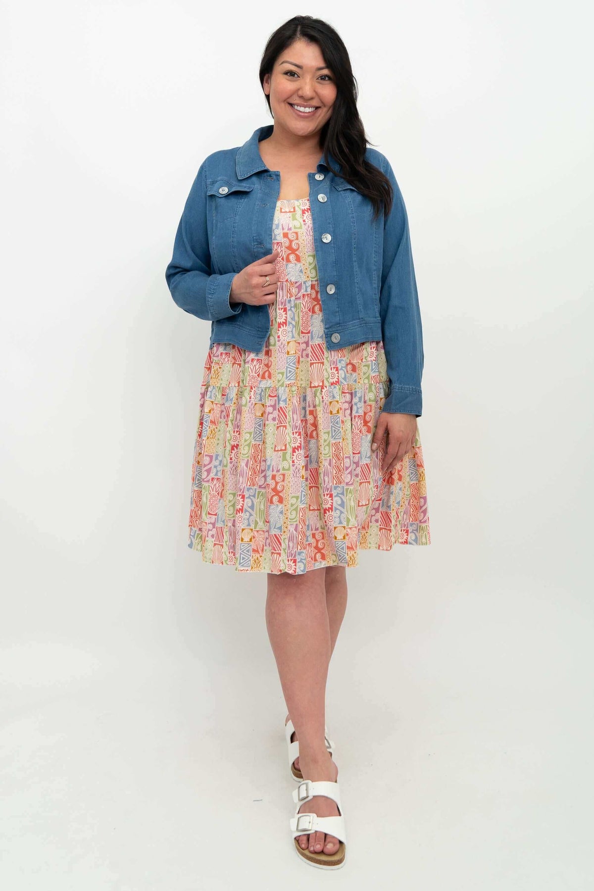 Model wearing colorful sleeveless dress layered with a denim jacket