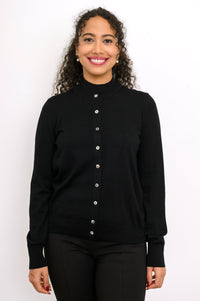 Close up front view of a smiling woman wearing a black fine knit merino wool crewneck cardigan.
