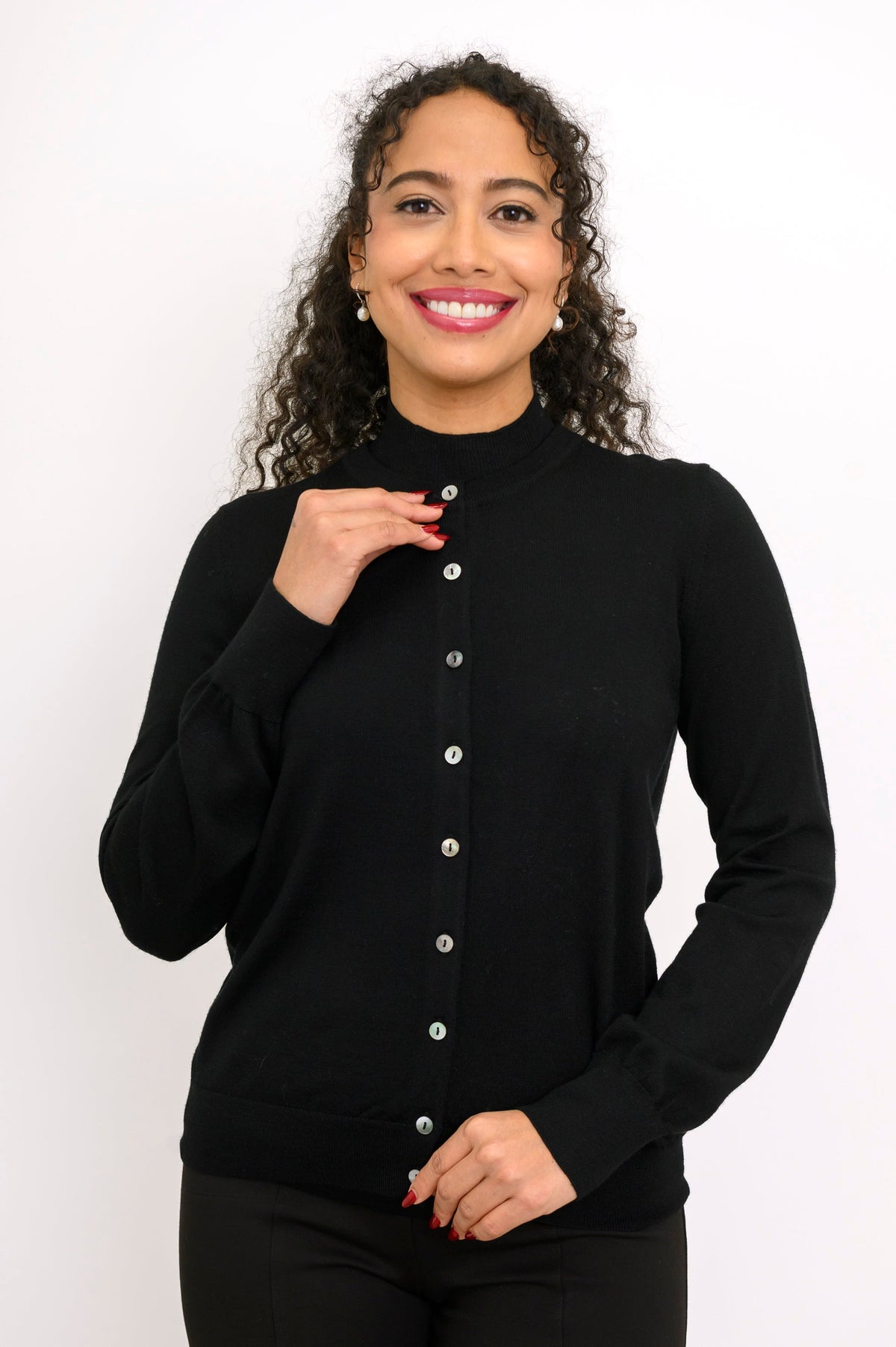 Woman modeling a monochromatic black outfit featuring a long sleeve crewneck cardigan and trousers.