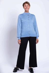Woman standing, wearing blue cardigan and black pants, hands at side