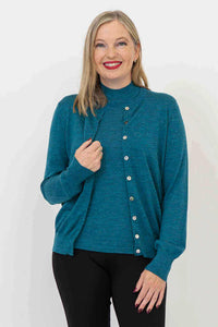 Full length view of a woman wearing a soft teal merino wool crewneck cardigan and black trousers.