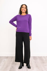 Front-facing view of a women's deep violet scoop neck knit top and dark pants, showcasing a classic autumn look.