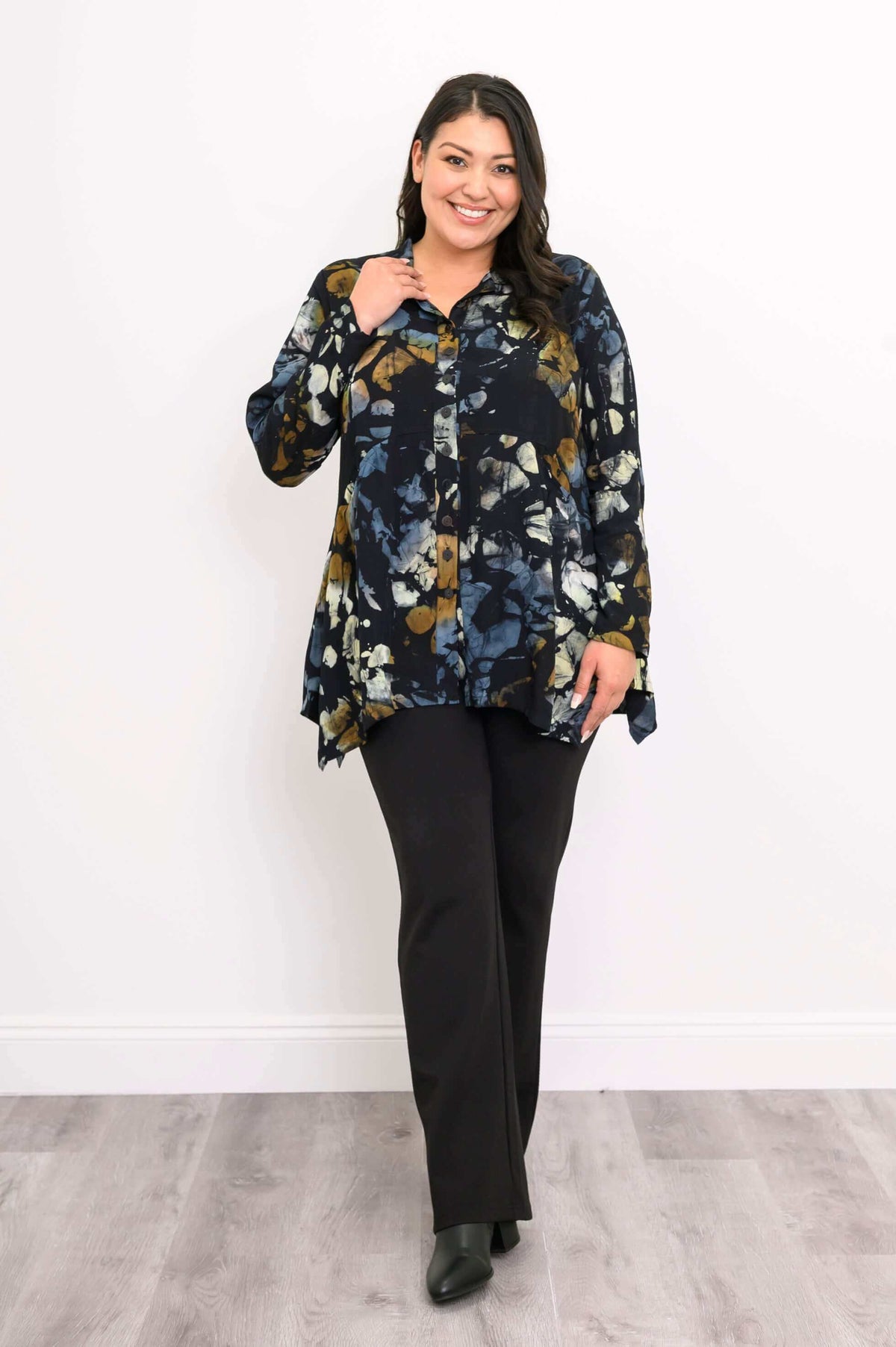 Woman smiles wearing Laney Blouse Night Bloom, hand near collar