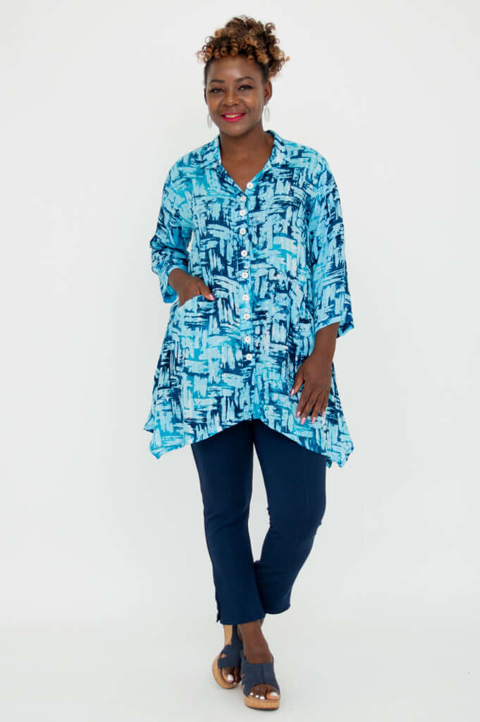Woman with hand in pocket wearing Laney Blouse in turquoise brushstroke pattern