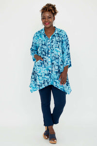 Woman with hand in pocket wearing Laney Blouse in turquoise brushstroke pattern
