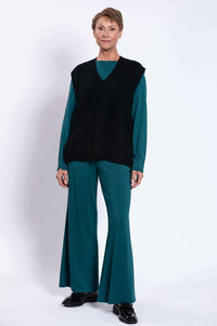 Model standing in a black V-neck sweater vest paired with teal outfit, front-facing