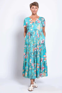 Woman standing with hands in pockets, modeling the Laurita floral tiered maxi dress