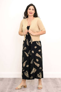 Woman layering a beige cardigan over a black and beige print dress