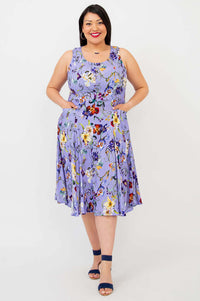 Woman smiling in a lilac floral A-line dress with hands in hip pockets