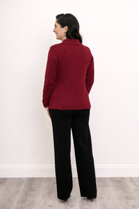 Back view of a woman wearing a fitted hip-length burgundy cotton sweater showcasing the clean tailoring and shoulder fit.
