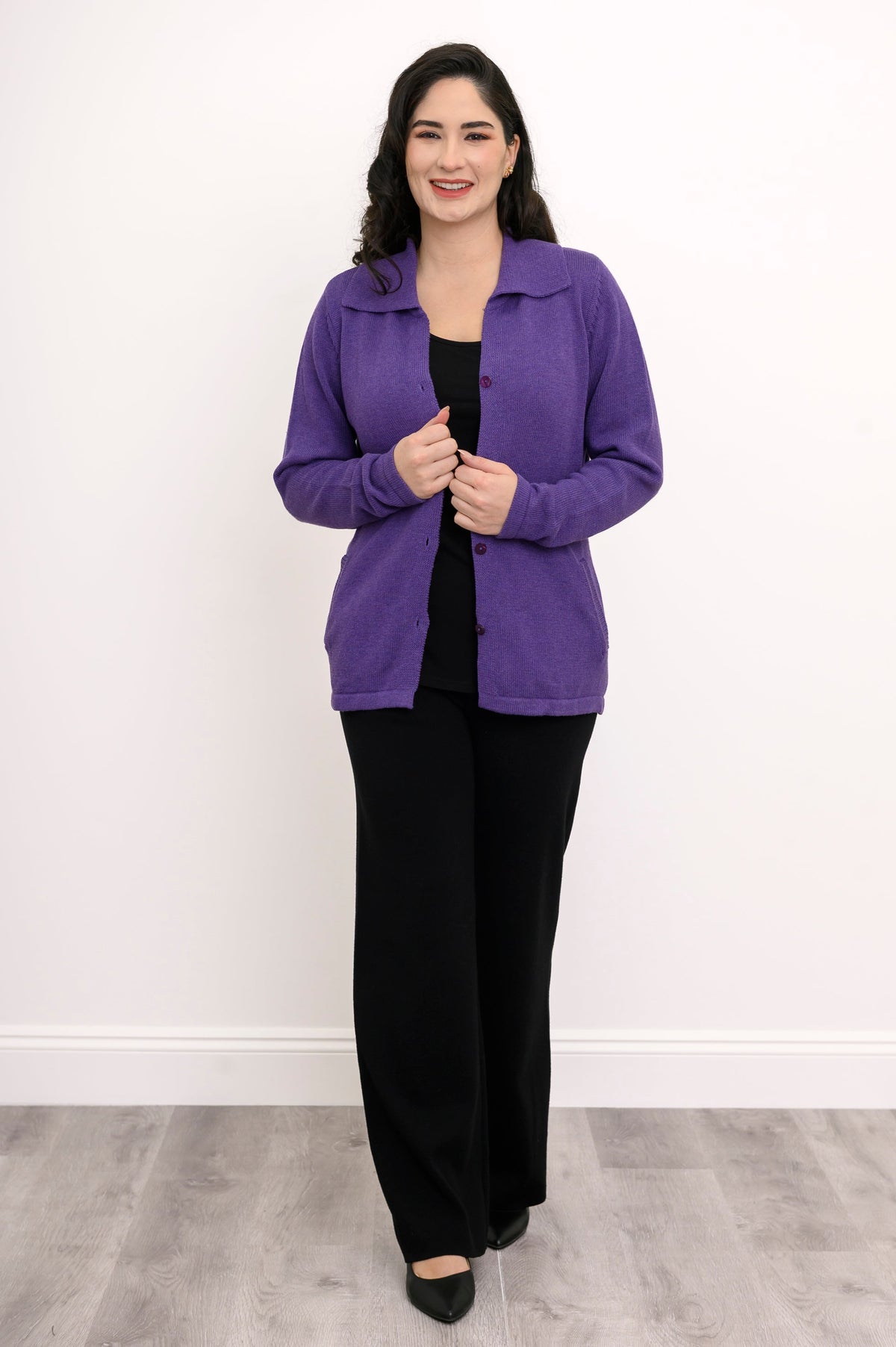 Model posing in a plum cotton cardigan layered over a simple black top, shown front-facing against a plain wall.