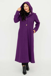 Woman wearing a long purple hooded coat with the hood up and hands in pockets