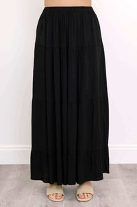 Detailed view of the lower half of the black maxi skirt and beige sandals