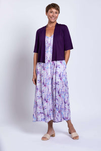 Woman smiling in a watercolor maxi dress paired with an open cardigan