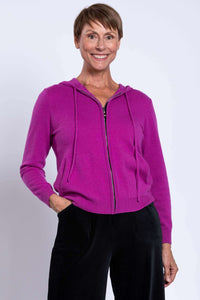Studio portrait of a model modeling a bright magenta pink long sleeve hooded cardigan with zip closure.