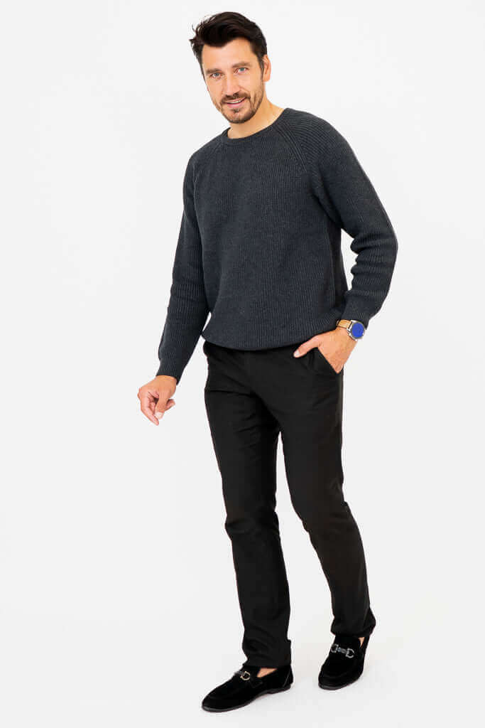 Man in charcoal ribbed sweater with hand in pocket, walking forward