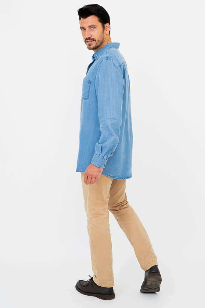 Man turning sideways, wearing light blue button-up shirt and tan pants