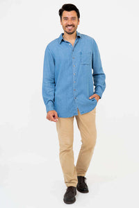 Man smiling in light blue button-up shirt with collar, hand in pocket