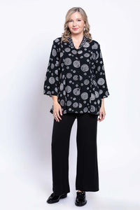 Model posing in black blouse with white concentric circles and matching black pants