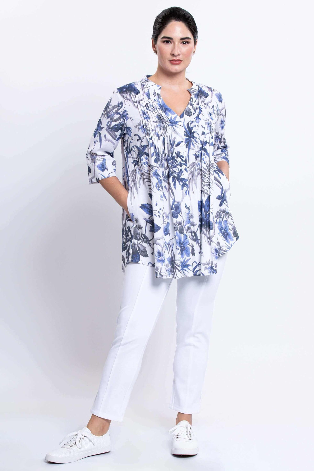 Woman with hands in pockets of Margate floral blouse and white pants