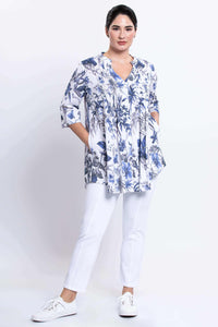 Woman with hands in pockets of Margate floral blouse and white pants