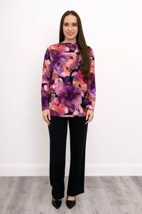 A-line pink floral print bamboo blouse with a boat neck, styled with black trousers against a white wall.