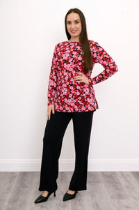 Model posing at an angle in a patterned pink three-quarter sleeve top, highlighting its loose, draped silhouette.