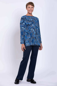 Woman in blue coral print long top standing in navy pants
