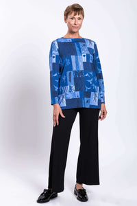 Woman modeling blue patchwork boat neck top with hands by her side, front angle