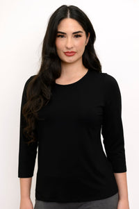 Close up front view of woman smiling while wearing a black 3/4 sleeve top and grey pants