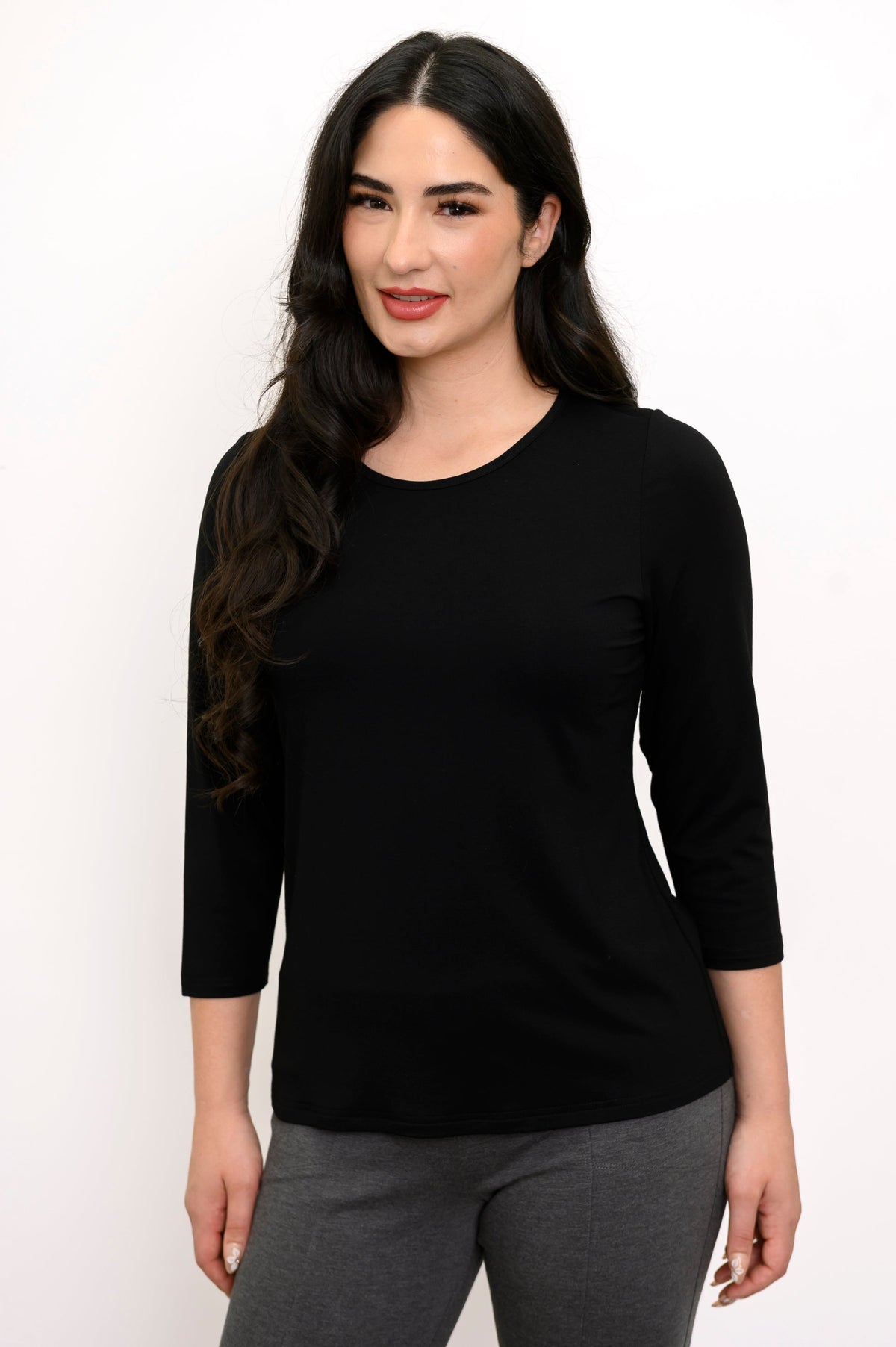 Front view of woman wearing round-neck black shirt and grey slim pants