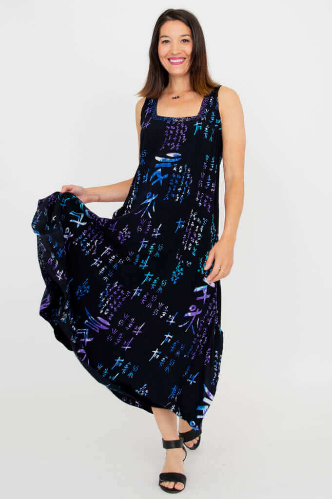 Woman twirling in a black maxi dress with blue and purple abstract print, showing flowy hem