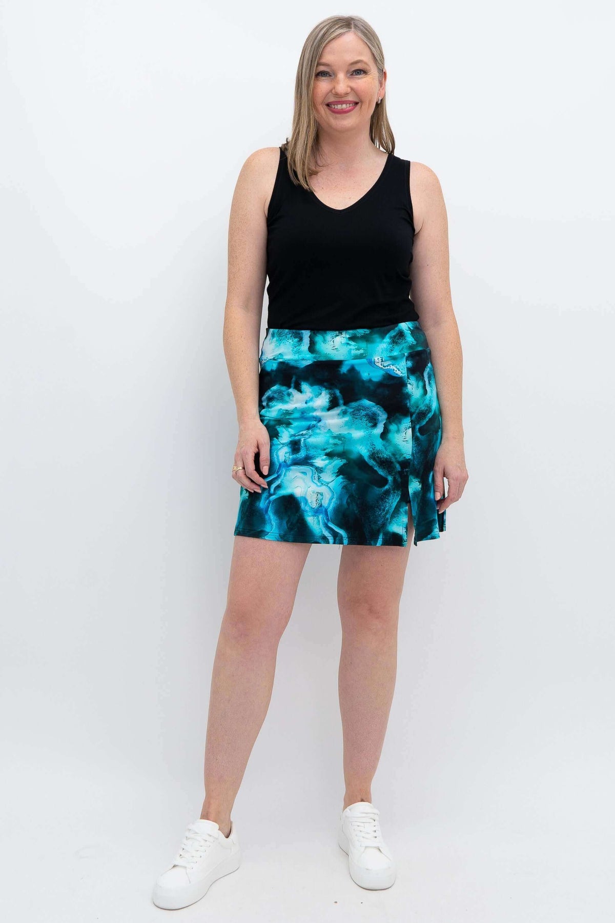 Woman modeling Melly Skort in Arctic Blue with black tank top, standing and smiling