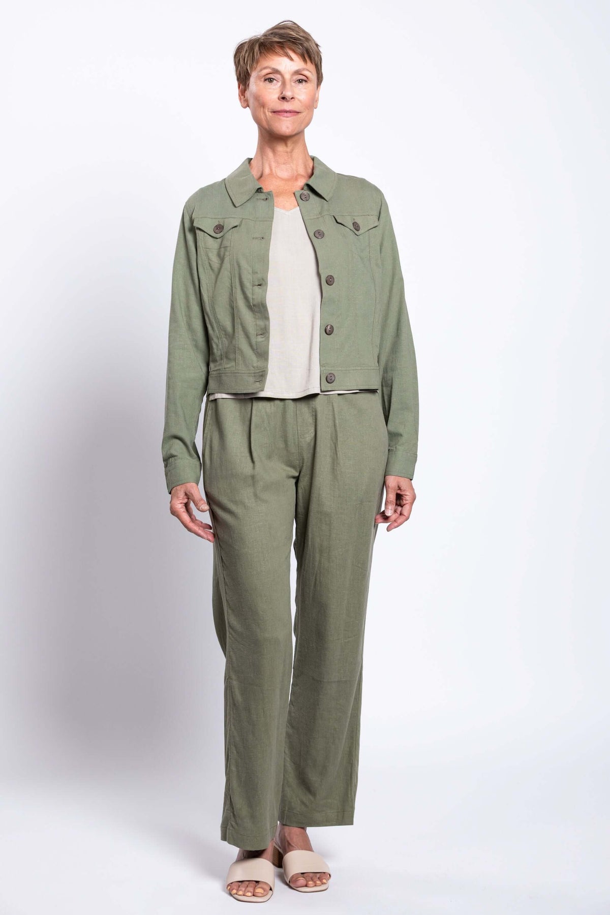 Full body view of model wearing a beige to and khaki green jacket and trouser set