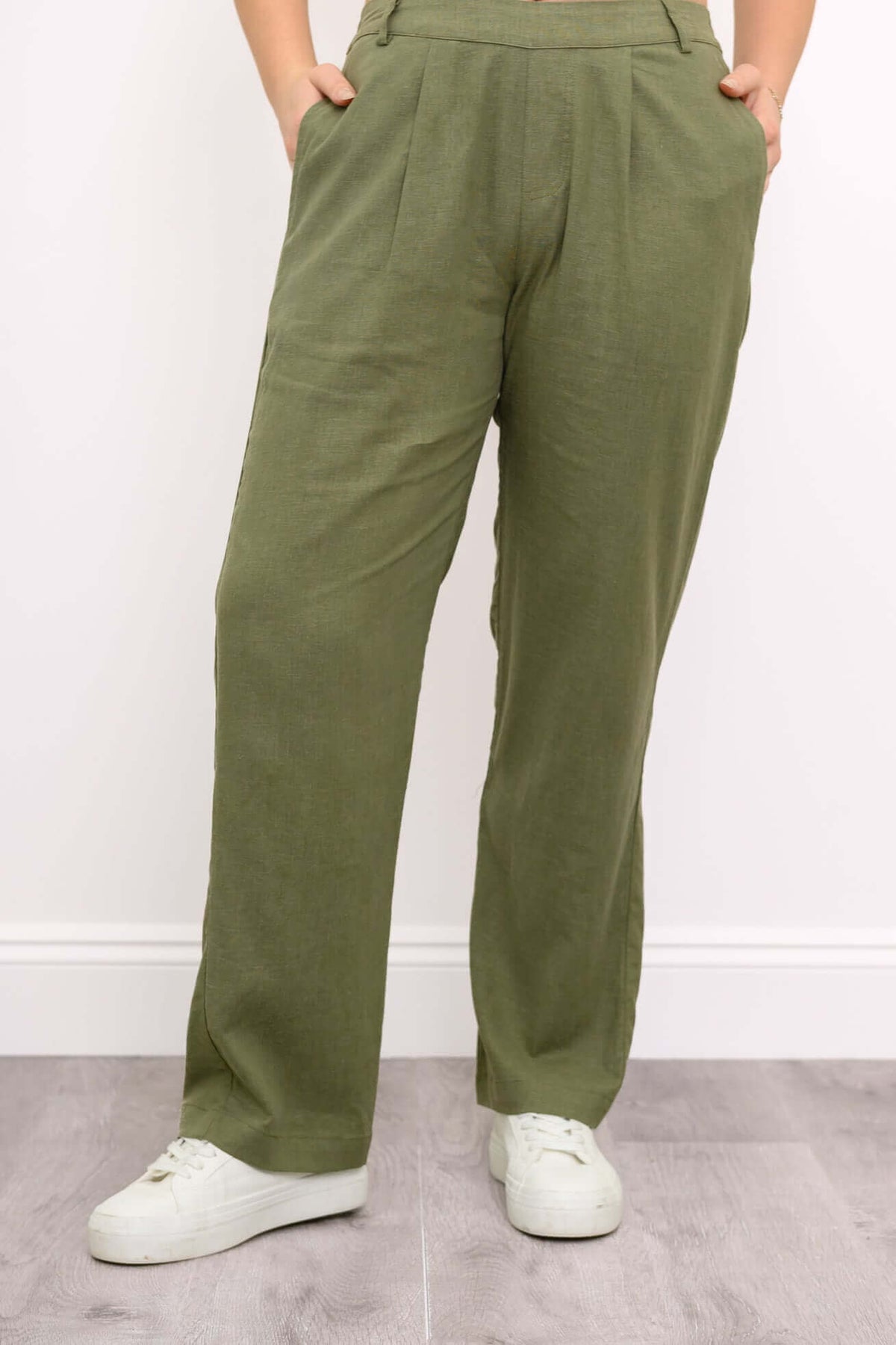 Front view of olive green pants styled with white sneakers