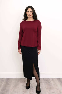 Woman in merlot boat neck top paired with black midi skirt