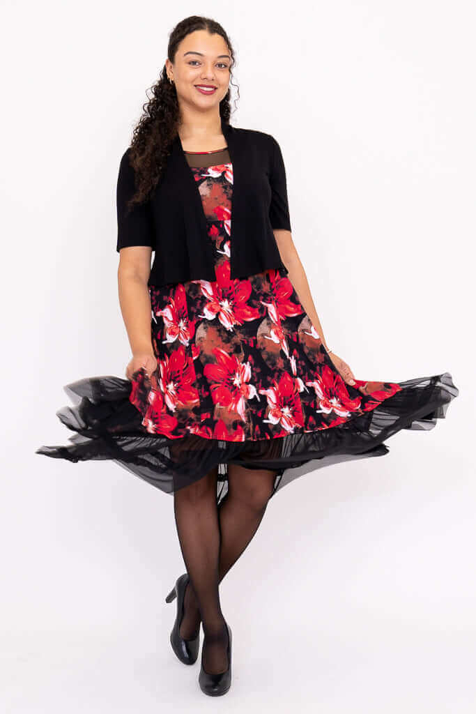 Woman twirling in mesh hem floral dress with black bolero cardigan and black heels