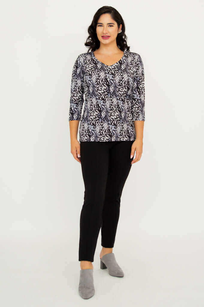 Model standing, front view in Mia Top Black Feather, black pants, and grey shoes